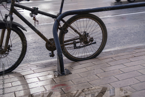 Abandoned high-end tuned sports bicycle, rusted and dirty with flat tires, chained to a pipe at a bike rack