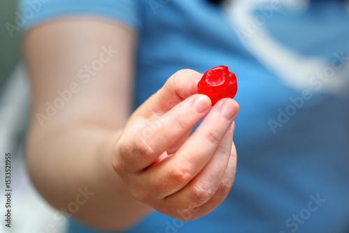 Woman's hand holding a large, bright red dried sweet cherry, showcasing natural snack and vibrant color