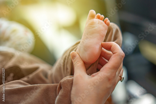 Mother's hand gently tickling her baby's foot during playful bonding time, capturing a tender moment of connection