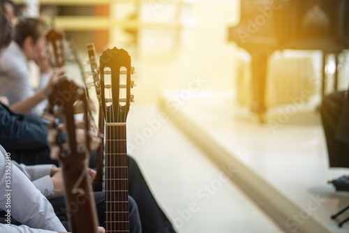 Row of guitarists with their instruments sitting before a stage, awaiting their turn while a colleague performs