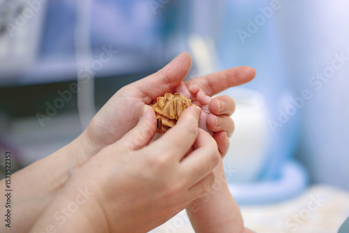 Mother gently massages her baby's palm with a honeysuckle wood ball for soothing relaxation and bonding
