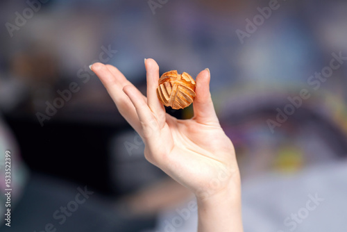 Elegant female hand holding a carved honeysuckle wood massage ball for therapeutic and relaxation purposes