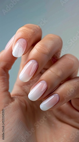 elegant nude-pink manicured nails and a gold ring adorned with a heart-shaped gemstone, complemented by a cozy white sweater sleeve.
