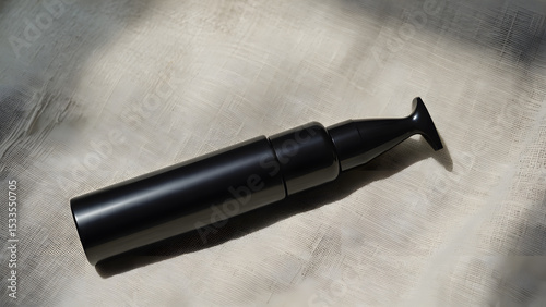 Black airless pump bottle on textured beige fabric