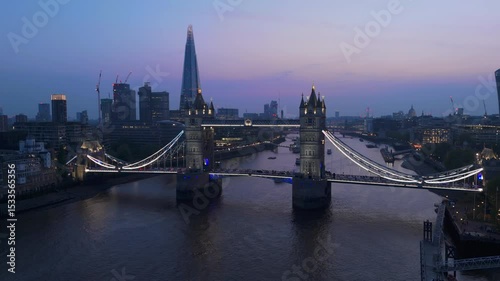 Aerial drone shots of Tower Bridge at twilight showcase Londons skyline against the Thames River, highlighting the citys beauty during enchanting evening hours that captivate all