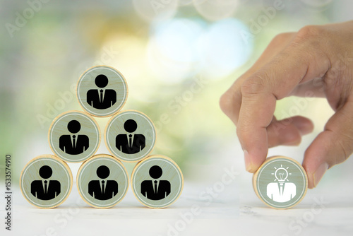 Hand chooses wooden toy stack with person icons for HR human resources or personal leader training skill or leadership and business team player challenge and organization management.