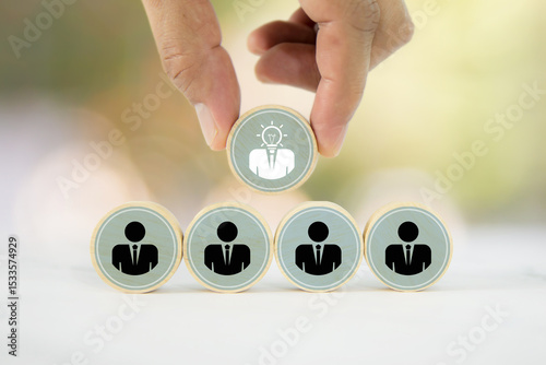 Hand chooses wooden toy stack with person icons for HR human resources or personal leader training skill or leadership and business team player challenge and organization management.