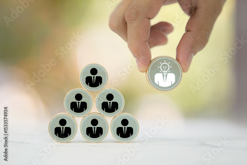 Hand chooses wooden toy stack with person icons for HR human resources or personal leader training skill or leadership and business team player challenge and organization management.