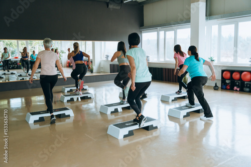 Group fitness class using steppers in gym for cardio exercise active lifestyle and wellness