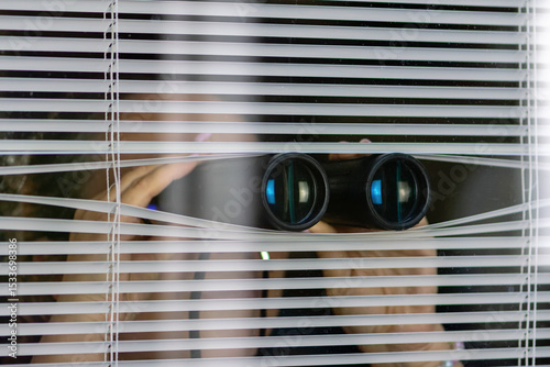 Tableau sur toile A man with binoculars observing through the blinds