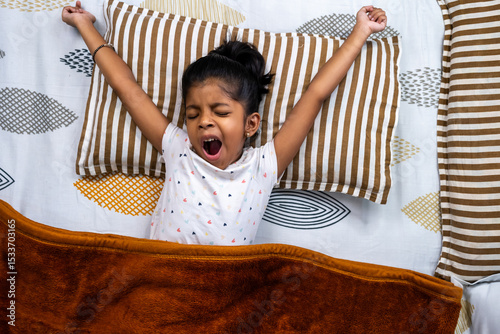 Child waking up and stretching in cozy bed in morning