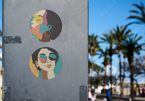 Two circular stickers are displayed on a sign beside palm trees.