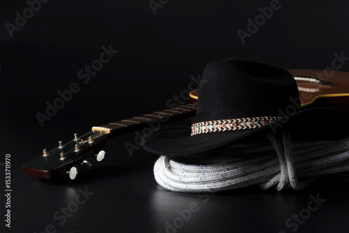 Chitarra e cappello da cowboy su sfondo nero con spazio per il testo.