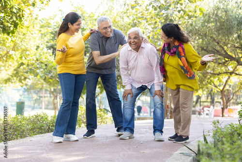 Group of happy indian senior men and women laughing and walking together in summer park. Retirement life, retired people enjoying in garden