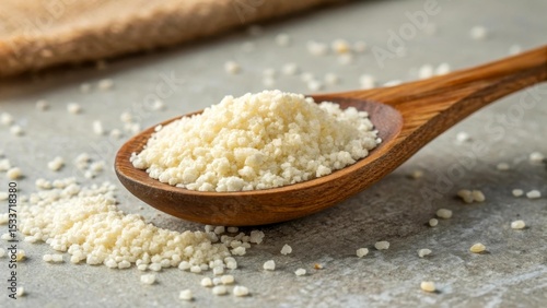 White granulated food on a wooden spoon on a textured background. Natural texture and simplicity create an atmosphere of coziness and eco-friendliness.