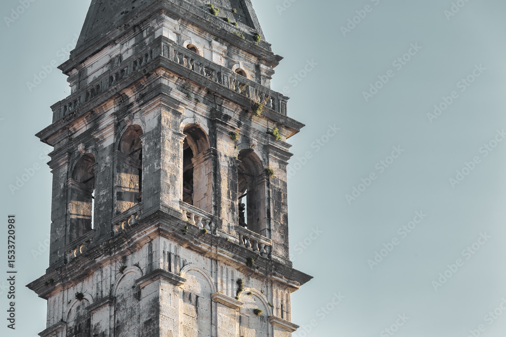 Fototapeta premium Close-up of historic church bell tower in Perast with weathered stone and classical architecture, Montenegro