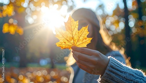 Faceless Person Examining Fallen Leaf in a Blurred Autumn Background