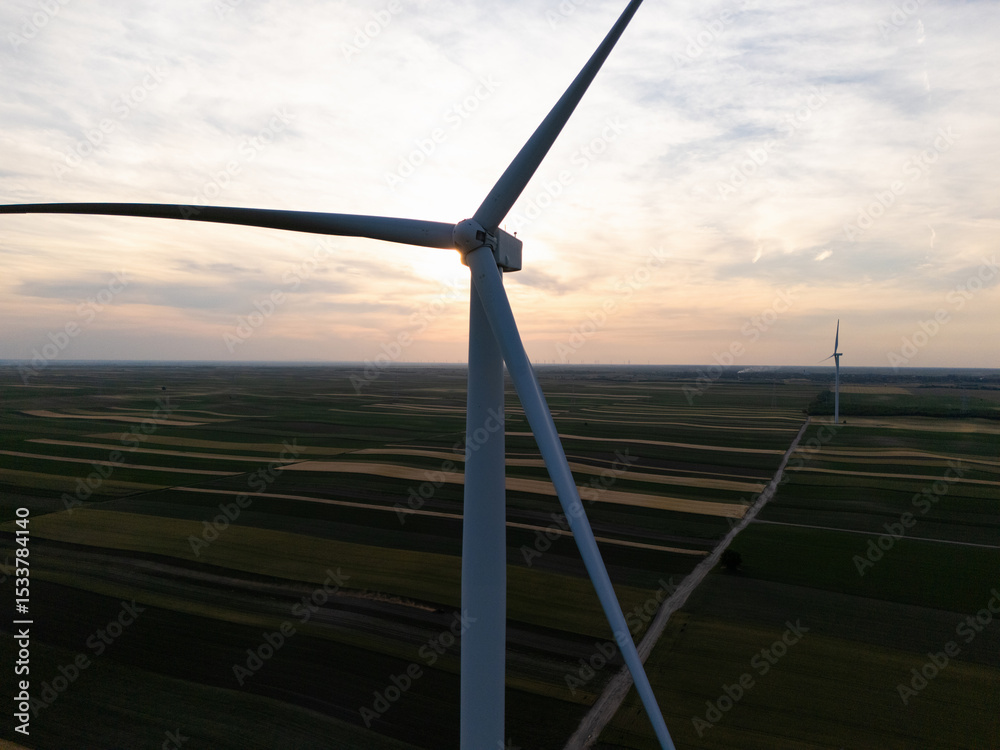 Fototapeta premium Aerial view of wind turbine on an agricultural filed at sunset. Close up of blades