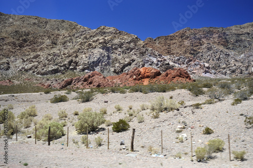 The stony foot of the mountain is strewn with large stones under the scorching sun. Desert hot arid landscape. photo