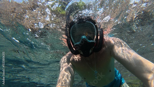 man swimming. Full face swimming mask. Snorkeling mask. Man in a swimming mask looks at the underwater world. Scuba diving on vacation.