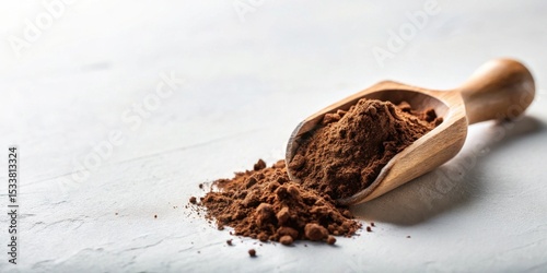 A wooden scoop overflowing with rich, dark brown cocoa powder spills onto a light gray surface