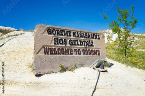 Welcome sign to Goreme in Cappadocia, Turkey. Stone monument with Turkish and English text stands under clear blue sky. Goreme is a very popular travel destination in Türkiye