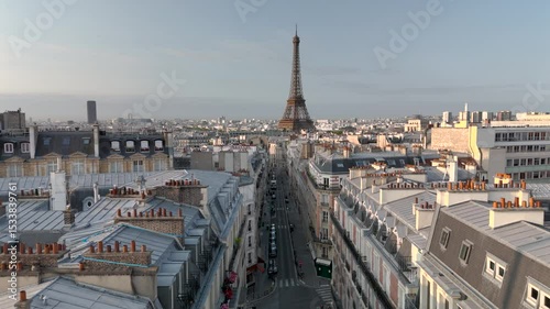 Aerial drone view of the sleepy streets of Paris, France, overlooking the famous Eiffel Tower and Champ de Mars at sunrise or sunset. Low motion over the rooftops. Cinematic 4k. Europe from above.