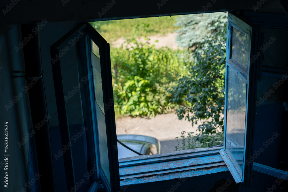 Fototapeta premium View from an open window showcasing a serene outdoor garden and parked vehicle during the day