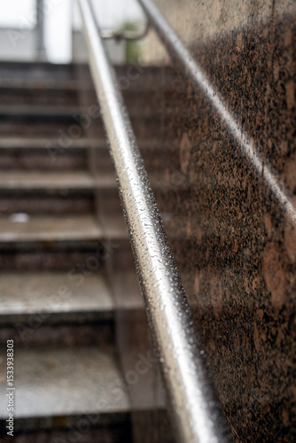 Round metal handrails at an underground passage exit glistening with raindrops after a fresh rainfall