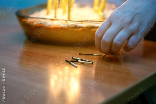 Burnt wooden matches arranged by hand near a festive cake with candle remnants, capturing a celebratory moment