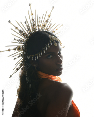 Regal silhouette portrait of a female model in an ornate crown and golden rim lighting, featuring a backlit profile that highlights elegant shape, glamorous pose, and a majestic, goddess-like presence