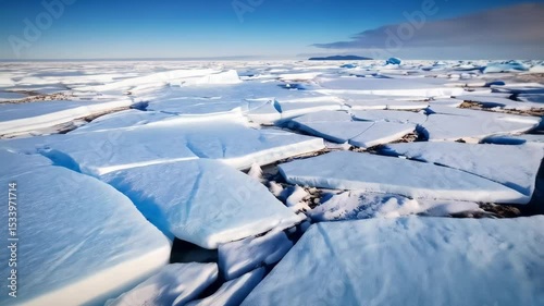 Frozen landscape of ice floes on a frigid arctic sea under blue sky with distant mountainous shorelines, an icy expanse of pack ice