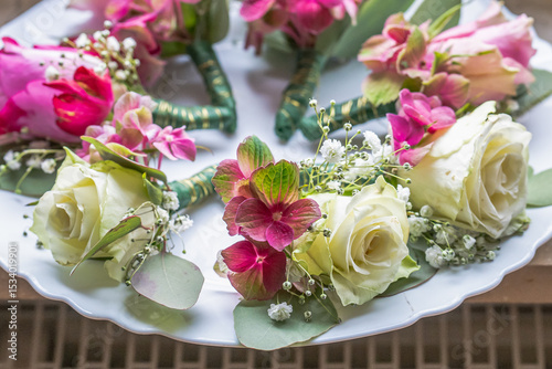 Small stylish boutonnieres on white marble plate, flat lay colorful many groom