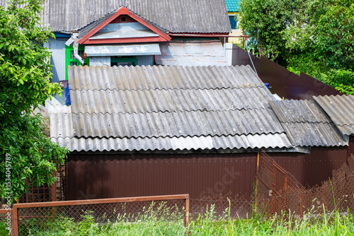 A small house with a corrugated metal roof and brown wooden fence