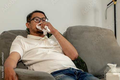 Ill male lying in bed at home, recovering from illness and resting during the day