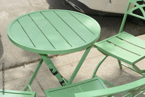 green garden table and chairs on a sidewalk in the city