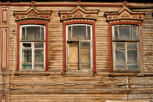 facade of an old building with windows, wooden walls and windows painted with weathered red-brown paint, old architecture