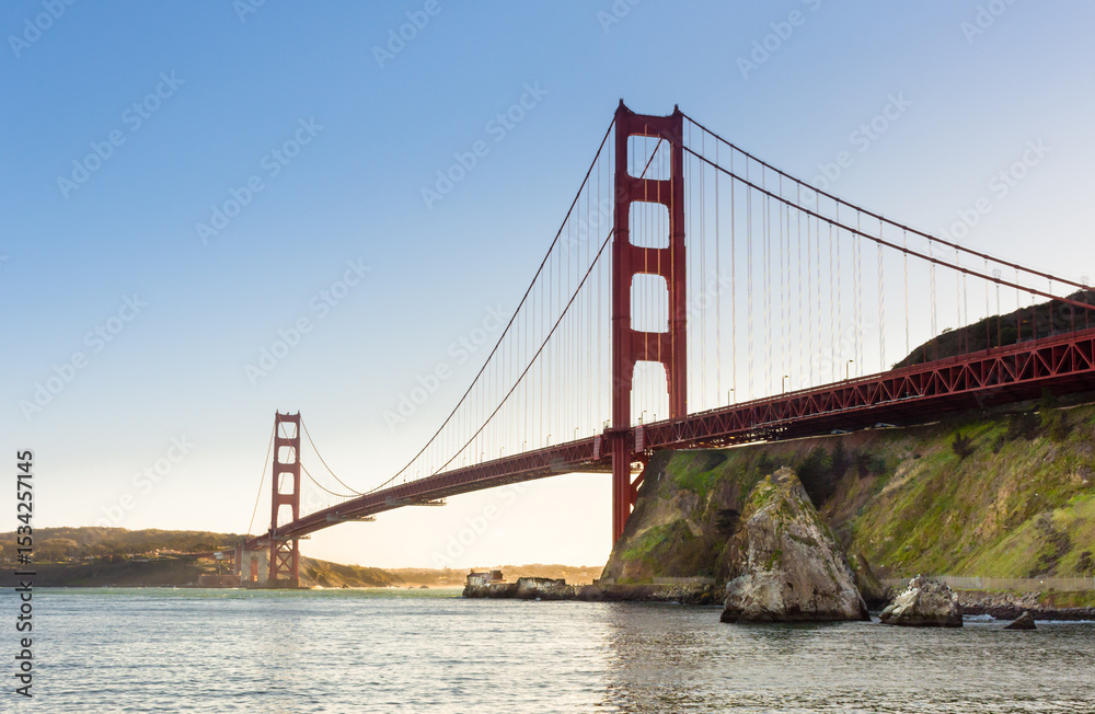 Golden Gate Bridge at sunset looking towards the Presidio of San Francisco from the opposite shore below the bridge Golden Gate Bridge at sunset looking towards the Presidio of San Francisco from the opposite shore below the bridge