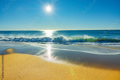 Sonnenschein über einem Sandstrand am Ozean