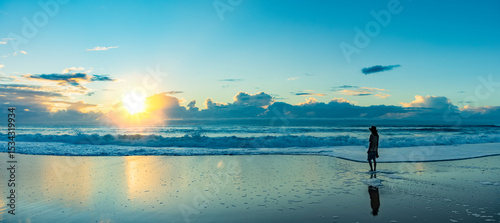Silhouette eines jungen Mannes mit Hut bei Sonnenaufgang am Strand