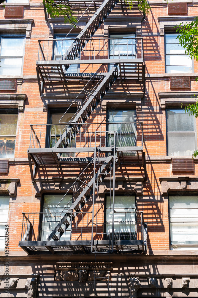Obraz premium An old red brick apartment building with fire escape stairs. New York City, USA
