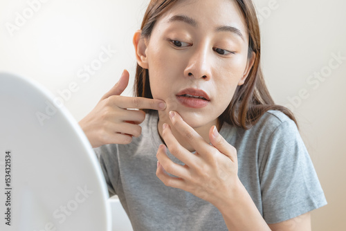 skin problem treatment. Women looking acne on her face in the mirror.