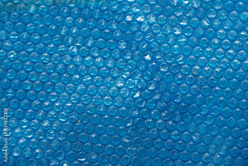 Blue bubble wrap texture with a smooth, glossy surface. The bubbles are evenly spaced, creating a uniform pattern. Ideal for backgrounds and abstract designs.