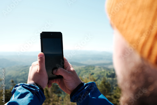 Close-up of hands holding phone to photograph mountain landscape in Zlatibor, Serbia. Travel blogger making video outdoor