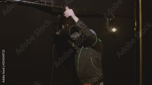 A male illuminator hangs a profile spotlight on a tripod