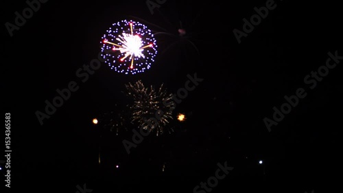 Golden, lilac and blue bright sparks of fireworks on the black sky