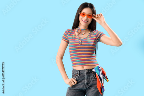 Beautiful young woman in rainbow t-shirt on blue background. LGBT concept