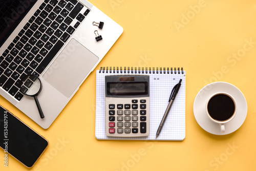 A modern workspace featuring a laptop and a coffee cup set against a bright yellow background