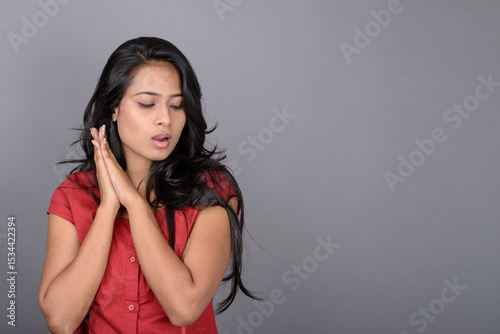 A confident young woman dressed casually in a red top and blue jeans, posing with jovial facial expressions and emotions