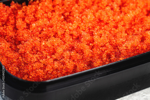 container with orange caviar, flying fish, Tobiko, on the table, caviar for rolls and sushi, close-up,
